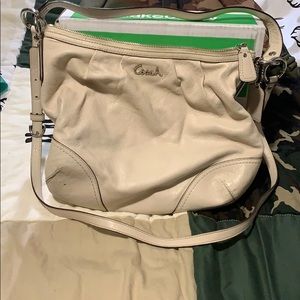 Cream colored crossbody or shoulder coach purse.